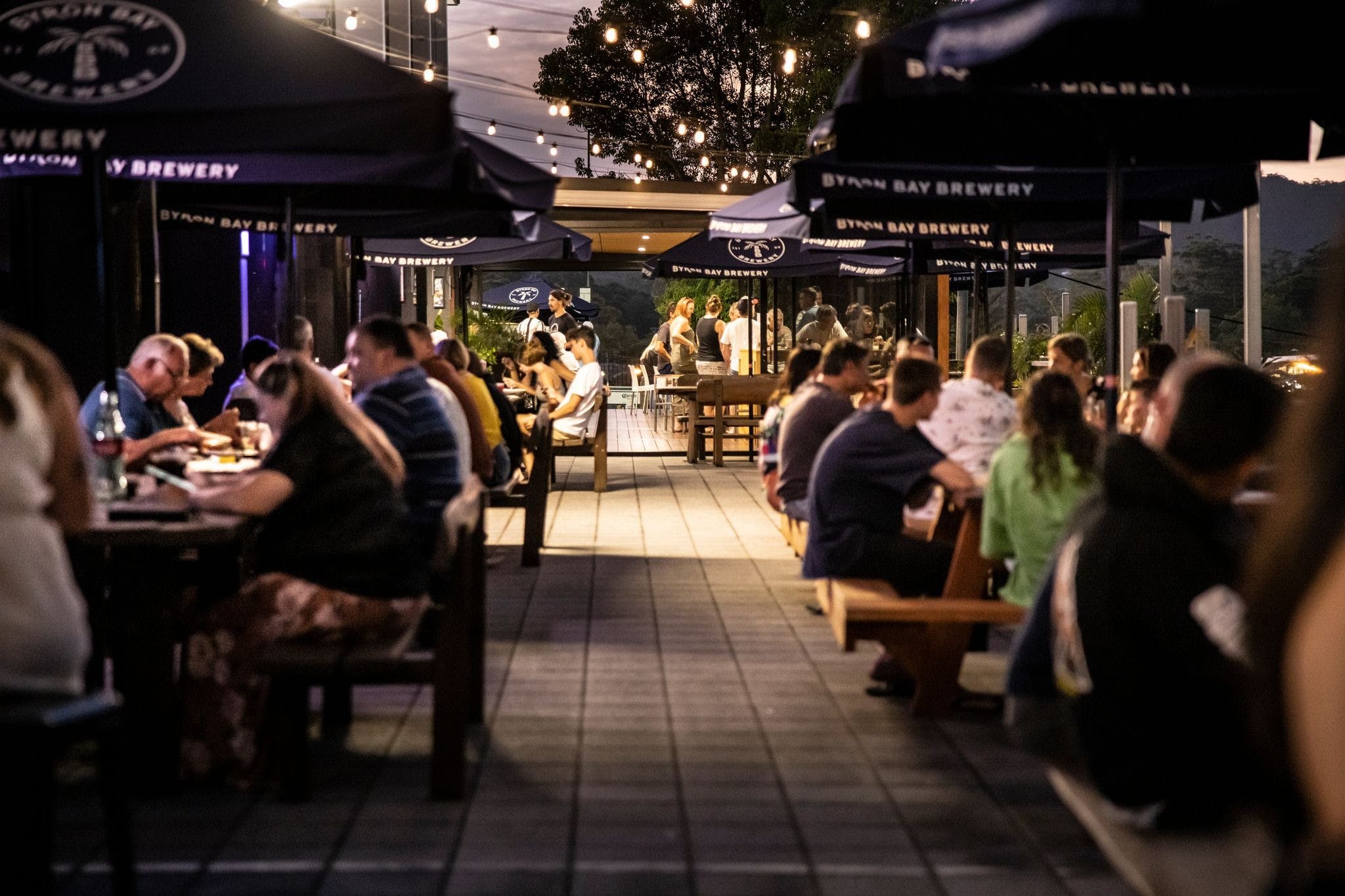 Looking through people sitting at outdoor tables, into the restaurant and to the kids area at sunset