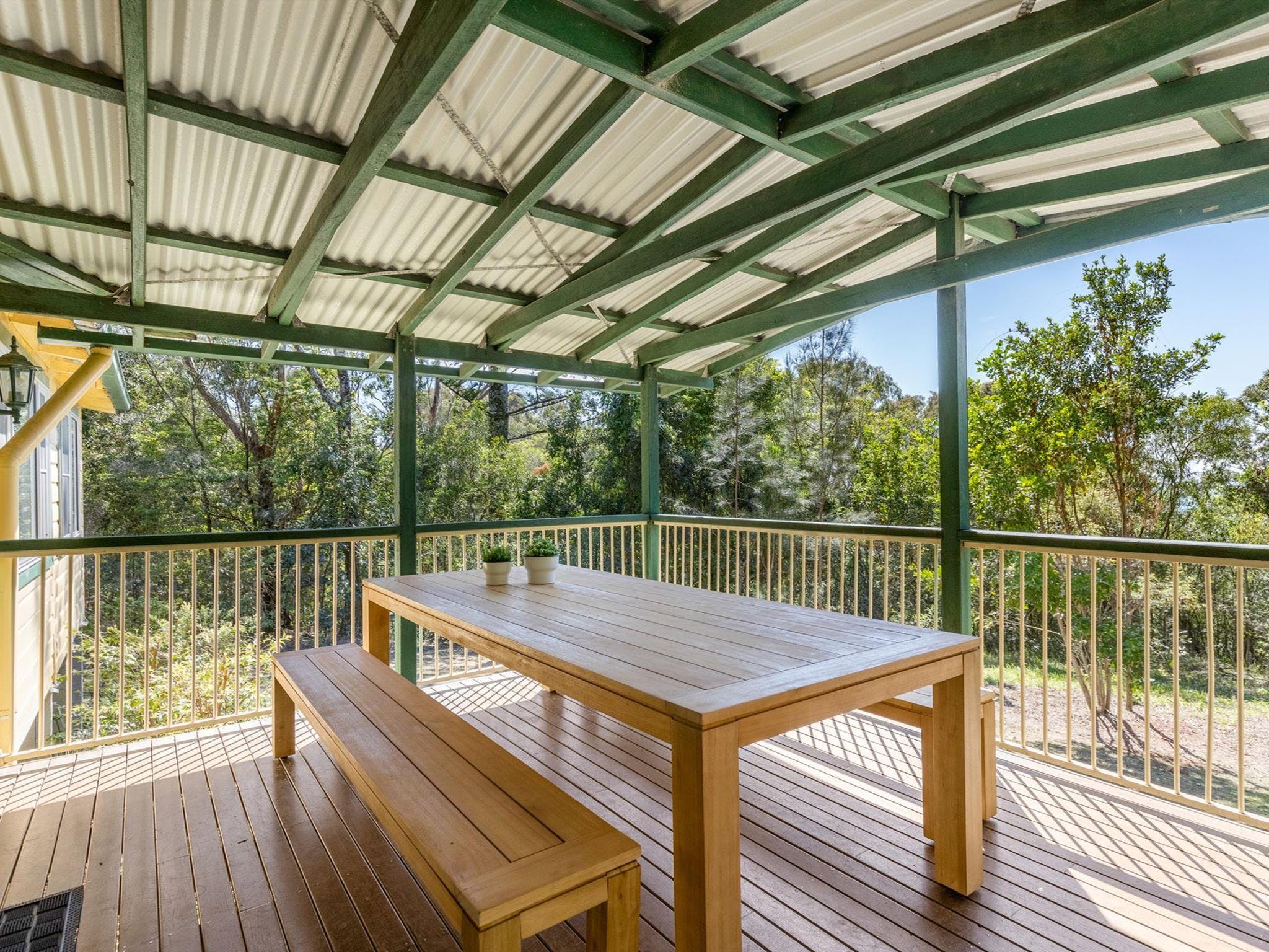 The verandah with outdoor table and benches at Tuckers Rocks Cottage in Bongil Bongil National Park.