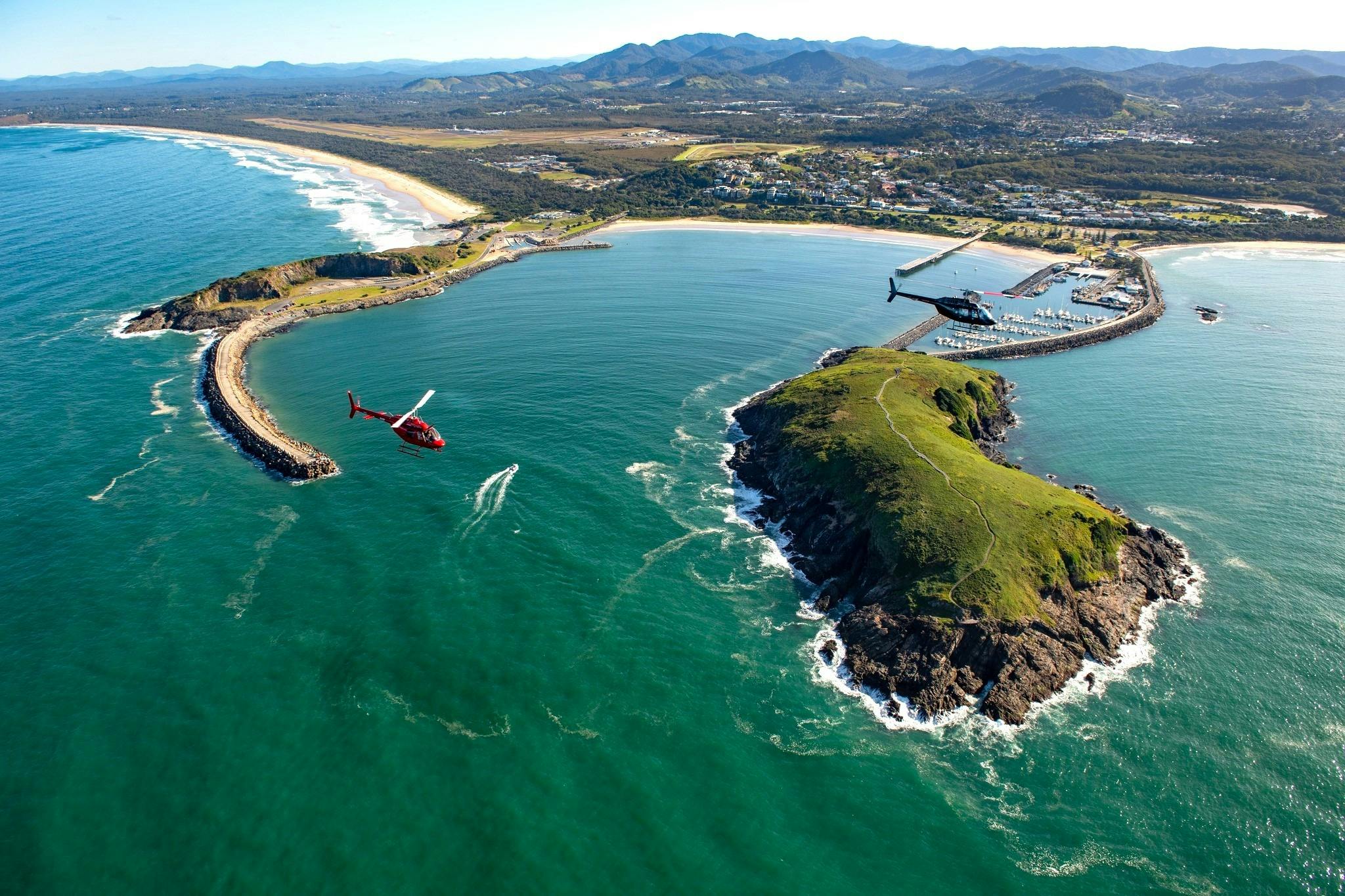 Coffs Harbour with the harbour, Muttonbird Island and two scenic helicopters in view
