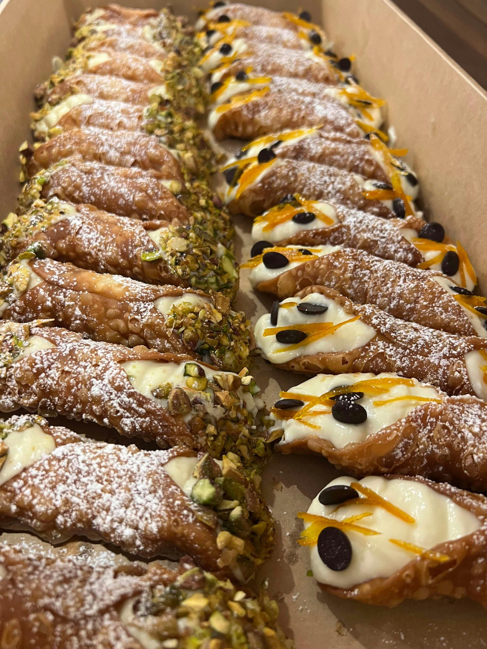 homemade Sicilian cannoli filled with pistachio or classic chocolate chips/candied orange